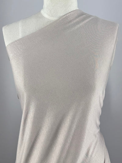A mannequin displays a sleeveless, asymmetrical top in Super Cheap Fabrics’ Cotton Jersey - Oatmeal (150cm), featuring lightweight fabric and one exposed shoulder, set against a plain gray background.