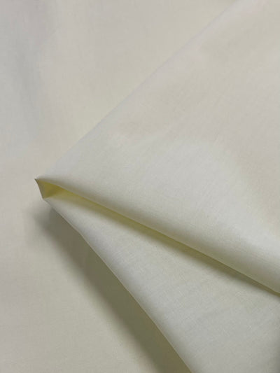 A close-up of Super Cheap Fabrics’ Poplin - Glass Green (112cm) displays its smooth, lightweight polyester cotton texture and subtle sheen under the light.
