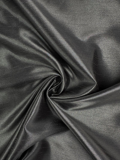 Shantung Satin - Charcoal by Super Cheap Fabrics is a metallic gray satin fabric, 150cm wide, with a smooth texture and elegant folds that catch the light for gentle highlights.