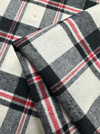Close-up of Super Cheap Fabrics' Suiting - Black Watch Plaid (147cm), showing the folded cotton polyester fabric with a textured twill weave and intersecting black, white, gray, and red plaid lines.
