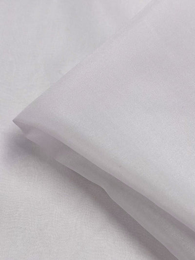 A close-up image of the Pure Silk Chiffon - Bridal Blush from Super Cheap Fabrics, showcasing a folded corner that reveals the fine texture of its smooth, white silk material under soft light. The crisp and clean appearance highlights the fabric's lightweight and delicate quality.