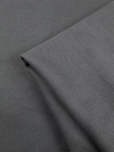 A close-up of two overlapping pieces of Super Cheap Fabrics’ Unbrushed Fleece - Charcoal - 185cm, highlighting the fine, smooth, and tightly woven texture of its high-quality cotton material.