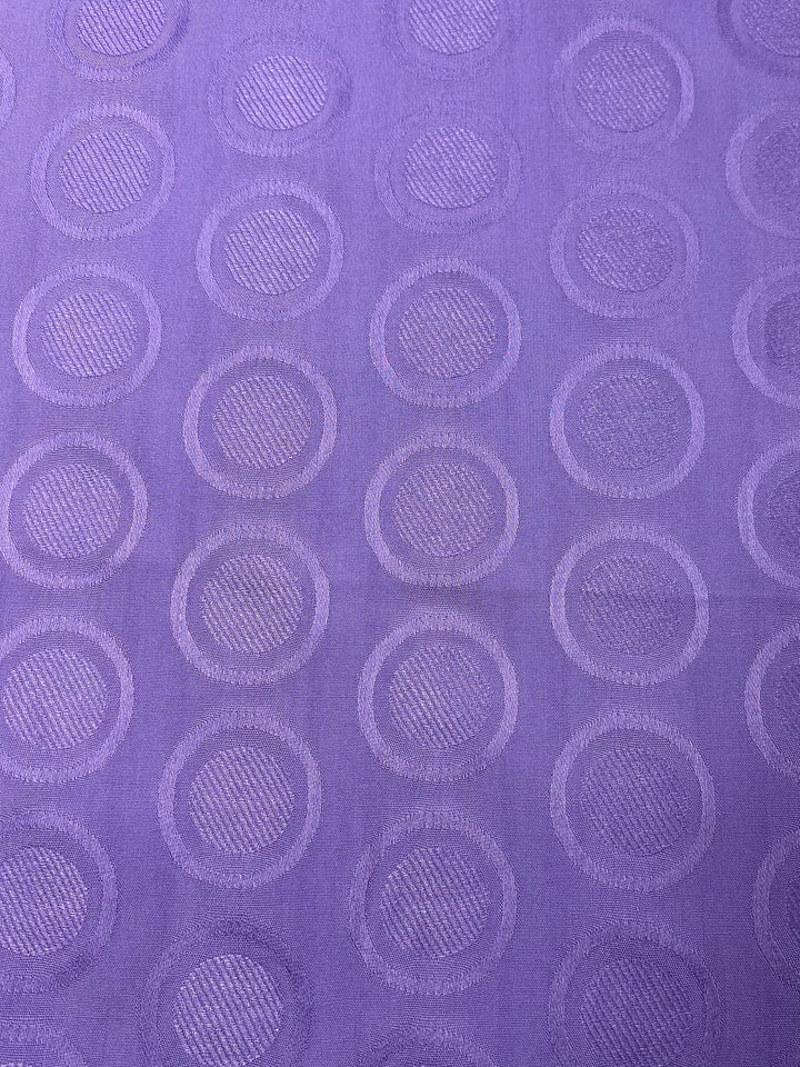 A light weight, purple Textured Rayon - Fairy Wren - 140cm from Super Cheap Fabrics featuring a pattern of regularly spaced, slightly raised circular shapes with a textured interior, creating a subtle, repeating geometric design. Perfect for crafting swing tops and dresses, the circles are evenly distributed across the entire material.