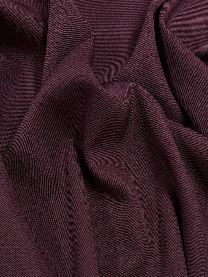 A close-up image of Twill Suiting - Madder Brown - 155cm by Super Cheap Fabrics with a smooth, slightly shiny texture. The medium weight fabric is creased and draped, creating soft folds and shadows.