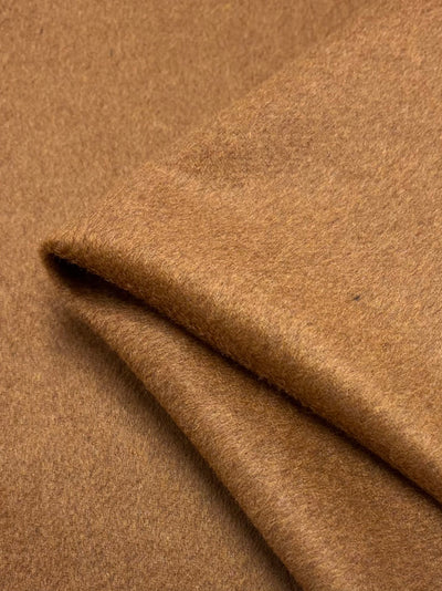 A close-up of a folded piece of Wool Cashmere in Glazed Ginger from Super Cheap Fabrics shows its smooth, slightly fuzzy texture and warm, cozy appearance, highlighting its extra heavy weight and quality.