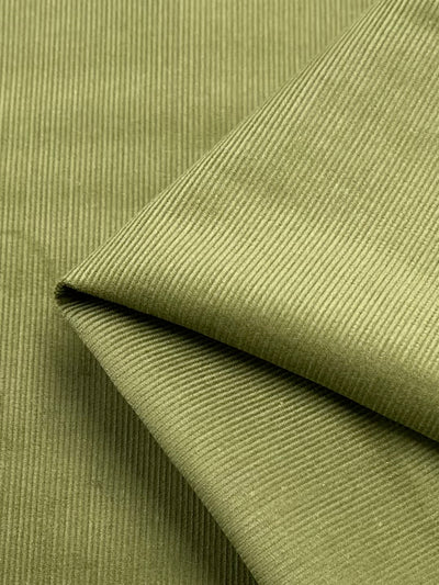 A close-up image of Super Cheap Fabrics' Micro Wale Corduroy - Cedar - 150cm, folded neatly. The texture showcases parallel ridges, highlighting the distinctive patterned design typical of corduroy material. Made from cotton fabric, it appears soft and thick, hinting at its durability and comfort in a lovely cedar color.