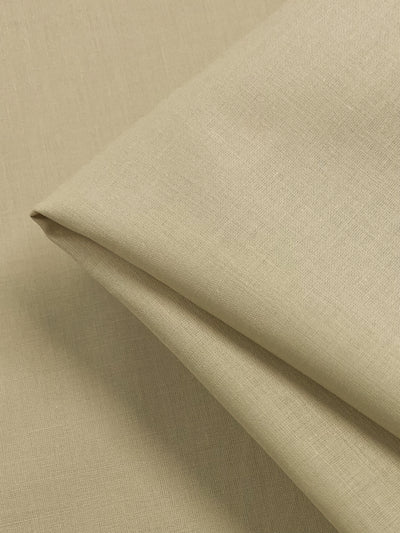 A close-up of Cotton Voile - Putty - 140cm by Super Cheap Fabrics with a soft texture, perfect for home decor. The fabric is partially folded, showcasing its smooth surface and natural weave. The image highlights the material's fine details, uniform color, and extra lightweight nature.