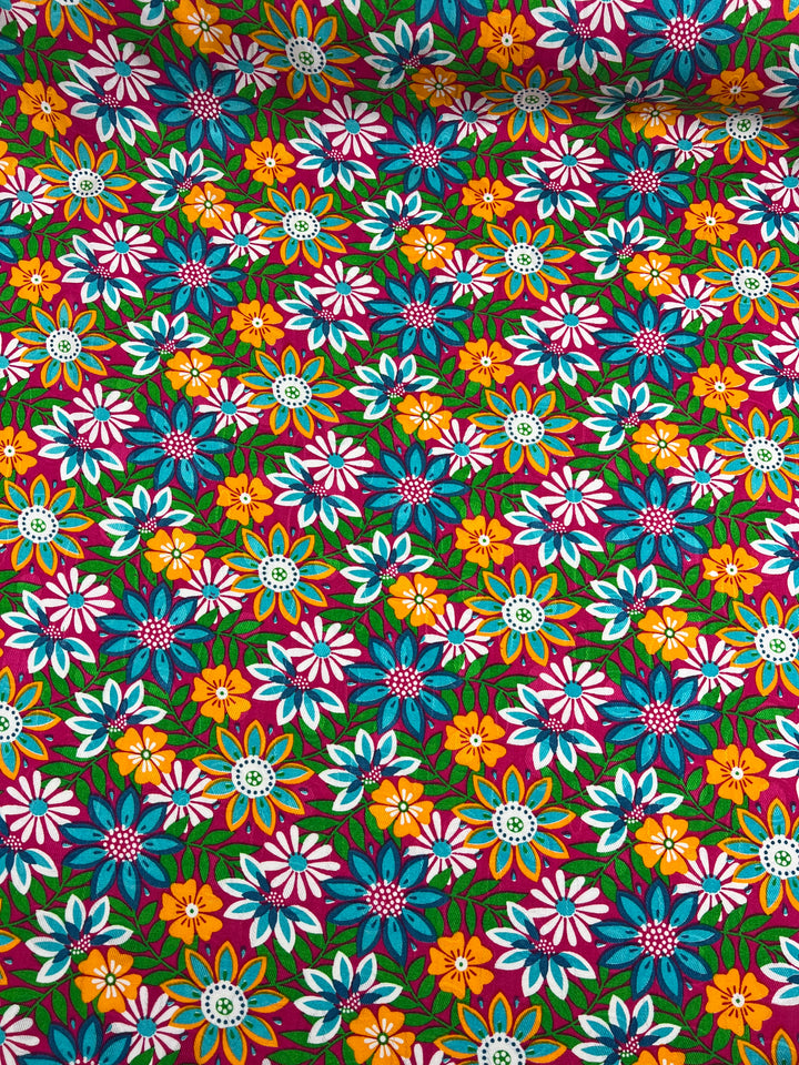 A vibrant multi-colored floral pattern featuring a variety of flowers in shades of blue, pink, orange, and yellow with green leaves set against a dark background. This lively display on light weight rayon fabric enhances its colorful charm. Introducing the "Printed Rayon - Lolita Spring - 145cm" from Super Cheap Fabrics.