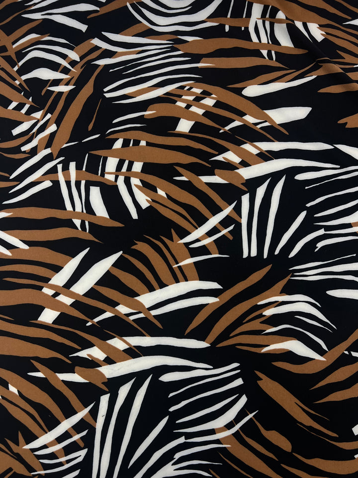Abstract pattern featuring black, brown, and white jagged brush strokes and lines, arranged in a dynamic and overlapping design. The predominantly black background adds depth to the medium weight fabric, perfect for multi-use clothing made from a durable polyester spandex blend. Introducing the Printed Lycra - Leafy - 150cm by Super Cheap Fabrics.