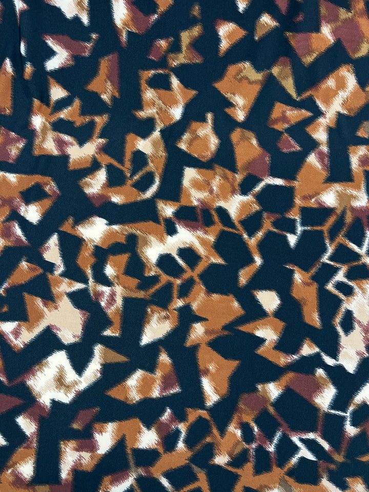 The Printed Lycra - Blurred Blocks - 150cm from Super Cheap Fabrics showcases an abstract pattern with irregular, jagged shapes in shades of brown, beige, black, and white. This medium weight polyester spandex blend fabric evokes an untamed wilderness with its overlapping forms creating a dense, textured effect.