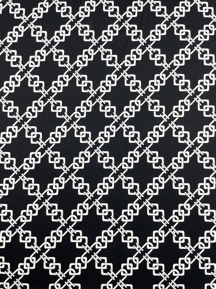 Introducing the Printed Lycra - Chained by Super Cheap Fabrics, this medium-weight polyester fabric features a seamless black and white geometric pattern of interconnected diamond shapes. The repetitive crisscrossing chain-link motif creates a uniform and structured appearance, making it ideal for multi-use applications across its 150cm width.