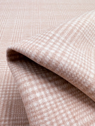 Close-up of light brown and white plaid wool blend fabric, showcasing a soft and textured pattern with overlapping folds. The heavyweight fabric features a small checkered design, suggesting a cozy and warm material, likely suitable for clothing or upholstery. Product name: Wool Flannel - Coral - 148cm by Super Cheap Fabrics.