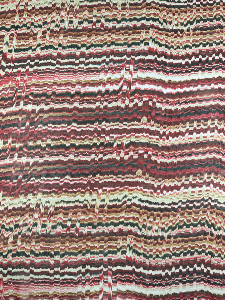 A close-up image of an abstract pattern with horizontal wavy lines in an array of colors including red, white, green, and black. The lines have a marbled, slightly distorted appearance, reminiscent of Pure Printed Silk - Celestial Warm - 140cm from Super Cheap Fabrics used in high-end fashion attire, creating a visually dynamic and energetic texture.