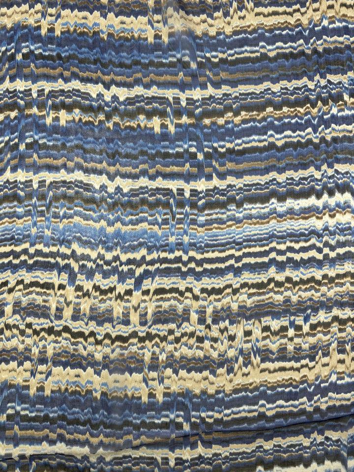 Abstract pattern featuring horizontal, wavy lines in various shades of blue, beige, and white. The undulating lines create a textured, layered appearance resembling geological strata or marbled fabric—evoking the elegance of high-end fashion and the sophistication of Super Cheap Fabrics' Pure Printed Silk Chiffon - Celestial Cool - 135cm.