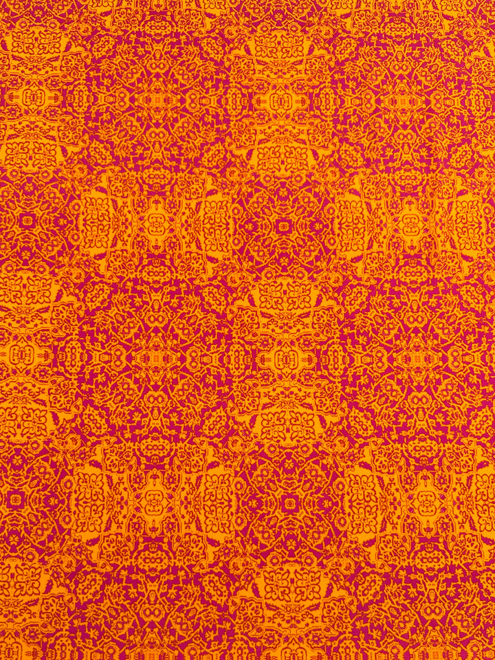 A vibrant medium-weight Polyester/Spandex fabric with an intricate, symmetrical pattern features red and purple ornate designs on an orange background. The design includes floral motifs and geometric shapes, forming a repetitive and detailed tapestry-like appearance. This is the Super Cheap Fabrics Printed Lycra - Volcano Mosaic - 150cm.