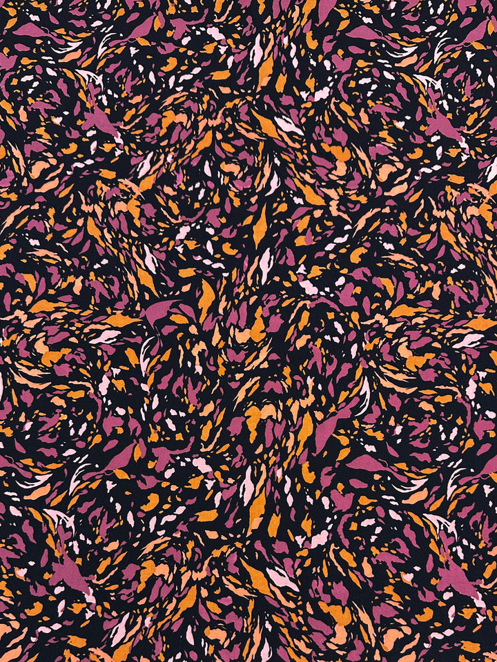 Abstract pattern with swirls and speckles in orange, pink, purple, and black. The design, printed on Super Cheap Fabrics' Printed Lycra - Clawed - 150cm, features a dynamic, flowing arrangement creating a sense of motion and depth. The dark backdrop allows the vibrant colors to stand out vividly.