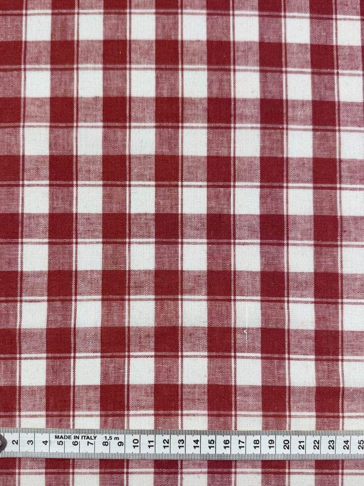 Super Cheap Fabrics' Linen Blend - Cranberry Check - 145cm features rust and white plaid, lightweight linen blend fabric with evenly spaced checks. Measuring tape at the edge shows up to 30cm. Ideal for versatile projects.