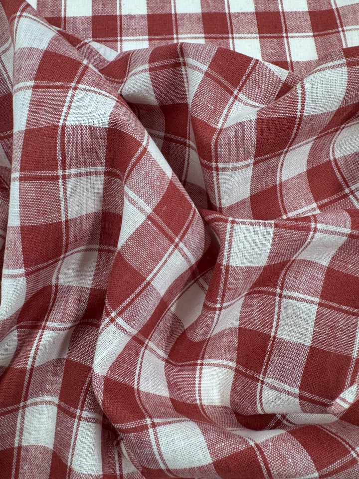 A close-up of Super Cheap Fabrics' Linen Blend - Cranberry Check (145cm) highlights its crumpled texture, intersecting lines, and checkered pattern. The lightweight material offers a soft, airy feel.