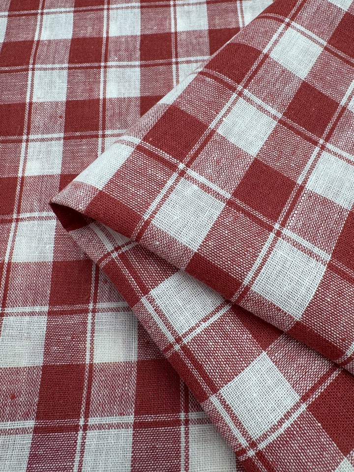 Super Cheap Fabrics' Linen Blend - Cranberry Check (145cm) features a lightweight, rust and white check pattern with woven texture, neatly folded for a timeless plaid look.
