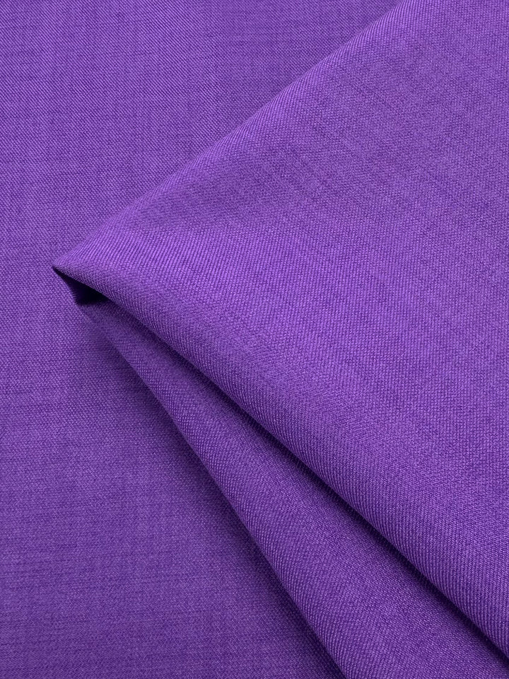 Close-up of folded Twill Suiting - Amethyst Orchid (150cm) by Super Cheap Fabrics, showing its smooth, slightly textured surface, even color, and fine diagonal weave in a vibrant purple shade.