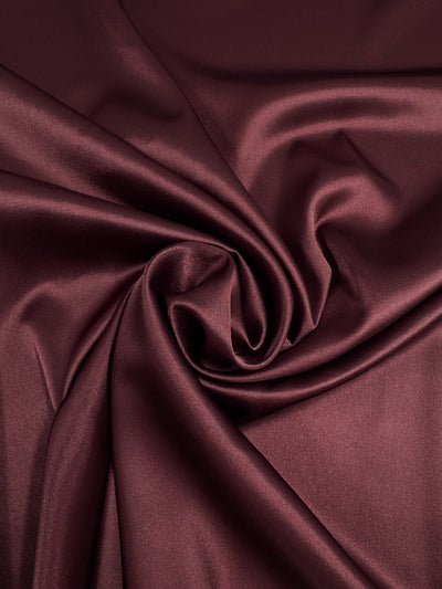 Satin Deluxe - Pomegranate by Super Cheap Fabrics is a rich burgundy satin (150cm) with a smooth, shiny texture and elegant swirling folds—perfect for luxurious nightgowns.