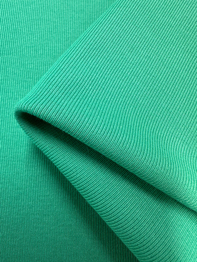 A close-up of two overlapping layers of Rib Knit - Peacock Green - 147cm by Super Cheap Fabrics, showcasing its ribbed pattern and fold.