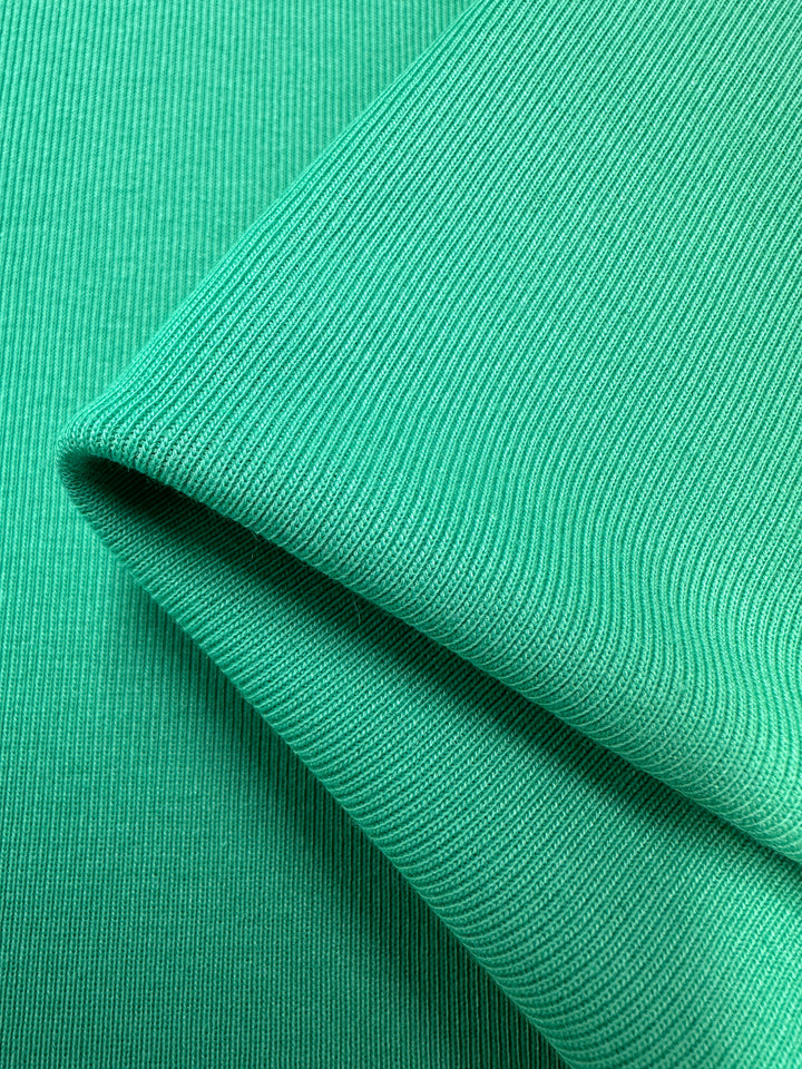 A close-up of two overlapping layers of Rib Knit - Peacock Green - 147cm by Super Cheap Fabrics, showcasing its ribbed pattern and fold.