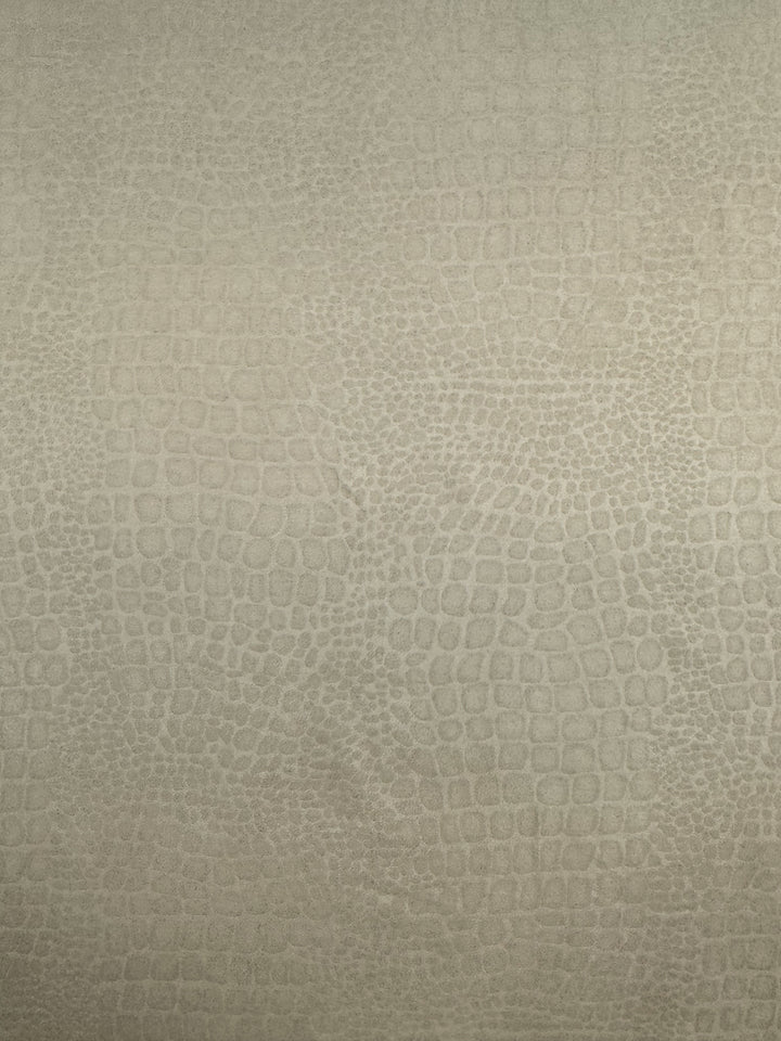 A textured surface with a soft, slightly shiny beige-toned pattern resembling reptile scales. Made from 100% polyester, the pattern is uniform and intricate, creating an appearance akin to crocodile or snake skin. The overall look is elegant and subtle. This is the Designer Faux Suede - Pepper Croc - 147cm from Super Cheap Fabrics.