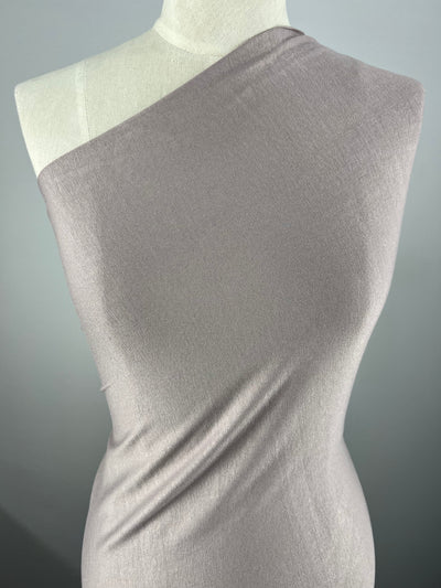 A mannequin wearing a one-shoulder, form-fitting dress made of light grey Rayon Lycra - Fawn - 150cm fabric from Super Cheap Fabrics. The dress has a smooth texture and drapes elegantly across the body, emphasizing the contours of the mannequin. The background is neutral and unobtrusive.