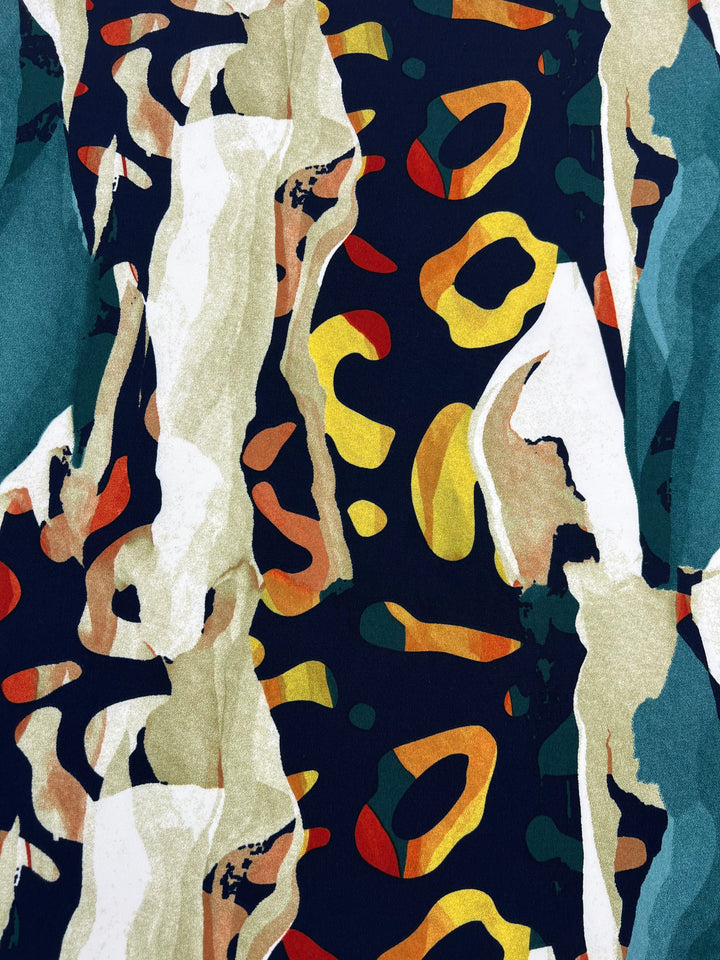 A vibrant abstract pattern featuring irregular shapes in shades of yellow, orange, and green on a dark blue background with teal backing, interspersed with beige and white streaks. The design has an organic feel, resembling a mix of natural elements and modern art. This is the Super Cheap Fabrics' Printed Lycra - Melt - 150cm.