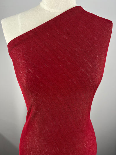 A close-up of a mannequin draped in Super Cheap Fabrics Lightweight Slub Jersey - Scooter Red - 150cm that appears semi-transparent. The textured knit fabrics cling closely to the torso, showcasing the generous stretch and fit. The background is a plain, light grey.