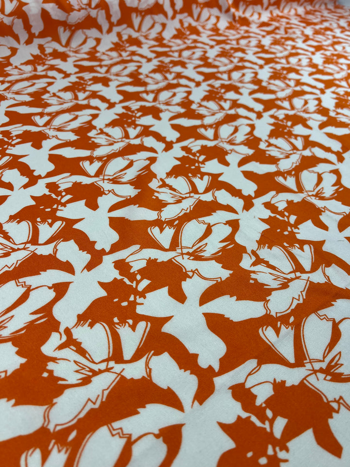 A close-up image of Super Cheap Fabrics' Designer Rayon - Tangelo - 140cm featuring a vibrant orange background with a repeating pattern of white bats in various flying poses. The bats are uniformly distributed, creating a dynamic and whimsical design, perfect for versatile fabric options.