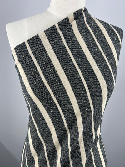 A dress form is draped in a Super Cheap Fabrics Linen Jersey - Sand Stripe - 150cm. The material has thick, vertical black stripes alternating with thinner, vertical white stripes. The dress form is angled slightly to the right against a plain, light gray background.
