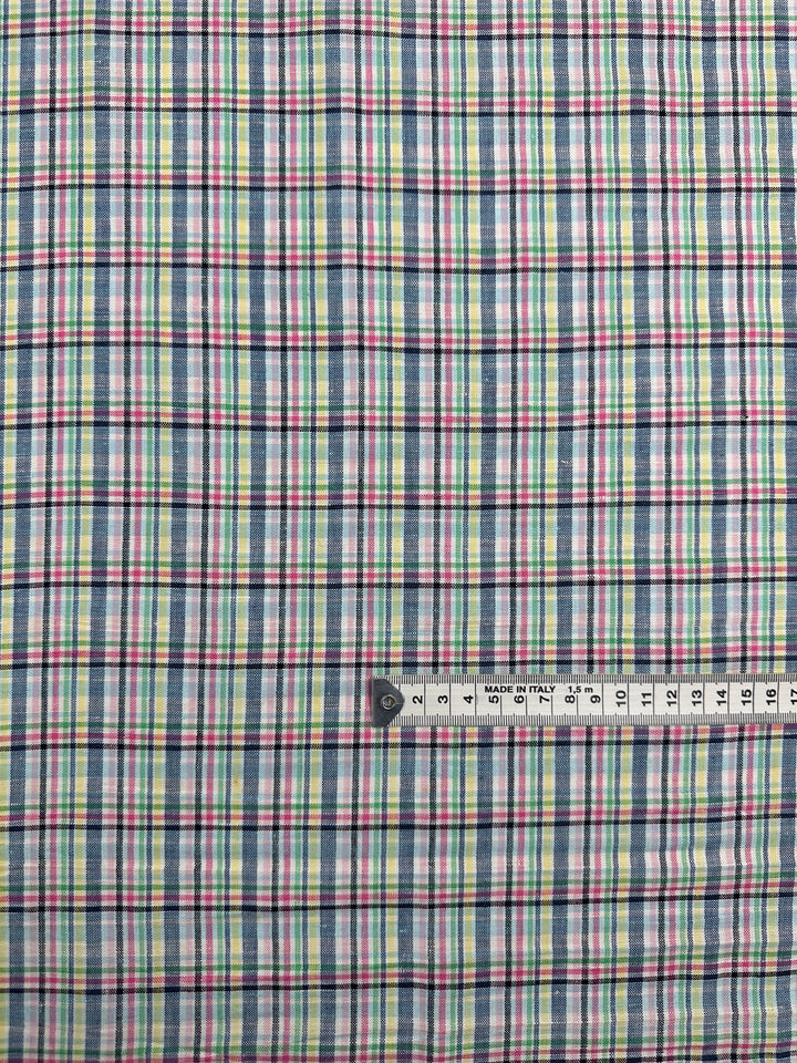 A close-up of Super Cheap Fabrics' Linen Blend - Tartan Prism (140cm), a lightweight linen-cotton tartan in blue, green, red, and white stripes with a measuring tape—ideal for summer projects.
