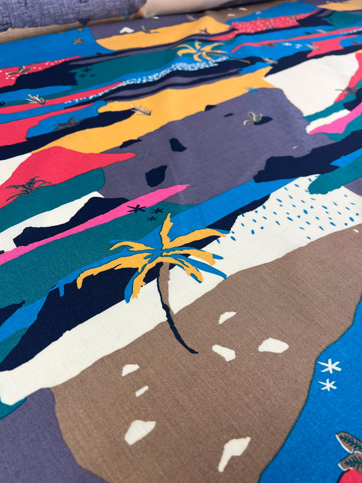 A vibrant, colorful fabric crafted from natural fibers with an abstract design featuring bold, irregular shapes in blue, pink, yellow, and purple. Among the patterns are small illustrations of palm trees and tiny starfish scattered throughout this lightweight Linen Cotton - Palm Tree - 135cm by Super Cheap Fabrics.