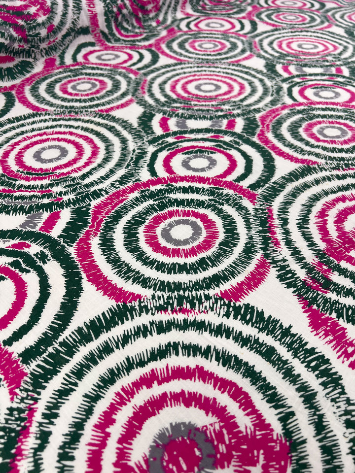 A close-up image of a durable fabric adorned with a pattern of concentric circles. The circles are predominantly pink and black, with white highlights, and are arranged in an overlapping manner across the entire Linen Cotton - Fuzz - 147cm by Super Cheap Fabrics material.