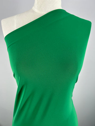 A green, one-shoulder top is displayed on a mannequin against a neutral background. The medium weight fabric appears smooth and sleek, with a snug fit that highlights the minimalist design and offers great elasticity. The fabric used is ITY Knit - Emerald - 150cm by Super Cheap Fabrics.