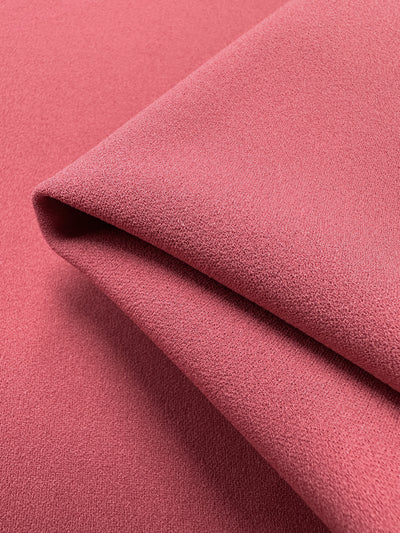 Close-up of folded Plain Scuba Crepe by Super Cheap Fabrics, showcasing its smooth texture and vibrant holly berry color. This medium weight fabric measures 150cm and features a soft appearance with a subtle grain, highlighting its quality.