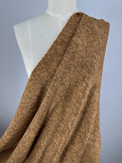 A dress form is draped with Super Cheap Fabrics’ Textured Knit - Foxtrot - 155cm, a soft, brown, textured knit fabric, and stands against a plain light gray background.