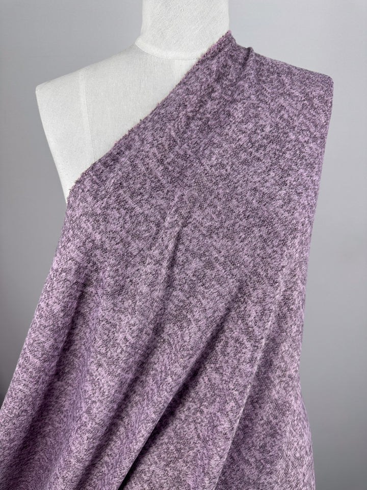 A white mannequin displays Super Cheap Fabrics’ Textured Knit - Orchid Marle - 150cm, a soft, medium-weight fabric in heathered lavender and gray tones, set against a plain gray background—ideal for unique wardrobe creations.
