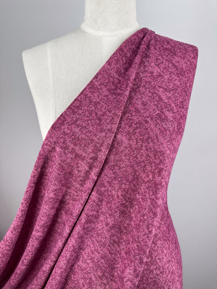 A dress form displays Super Cheap Fabrics’ Textured Knit - Rose Violet - 150cm, draped diagonally to showcase its heathered mauve tones against a plain, light gray background.