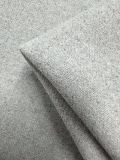 A close-up of Super Cheap Fabrics’ Wool Cashmere - Silver Marle (150cm) shows its luxurious softness, thick texture, and slightly fuzzy silver-gray surface with a corner folded over.