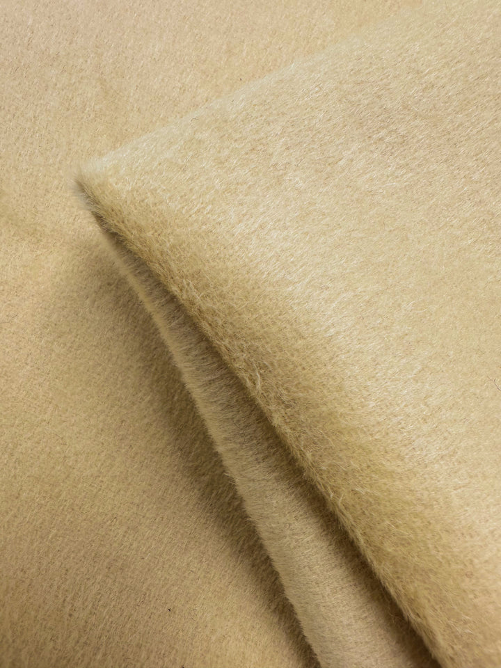 A close-up of Wool Cashmere - Banana - 150cm by Super Cheap Fabrics shows its light beige, fuzzy texture and fine fibers, emphasizing the plush, luxurious softness characteristic of this premium fabric.