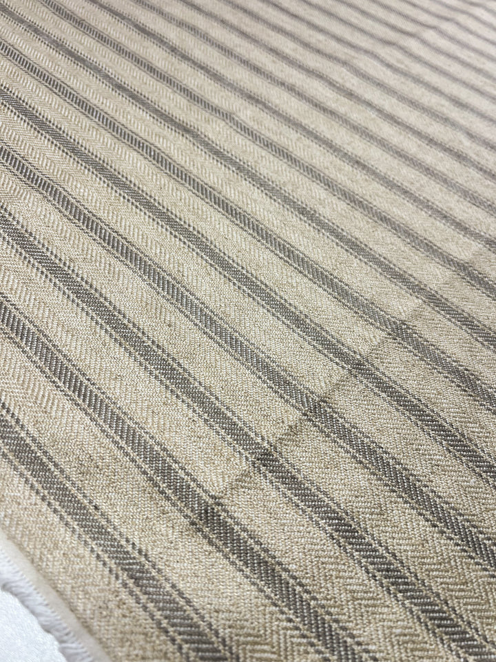 Close-up of Super Cheap Fabrics' Upholstery Herringbone - Silent Storm - 145cm with dark brown stripes running diagonally across the material. The texture appears rough, highlighting the woven pattern in each stripe. The background shows more of the same durable fabric, reflecting a consistent pattern throughout.