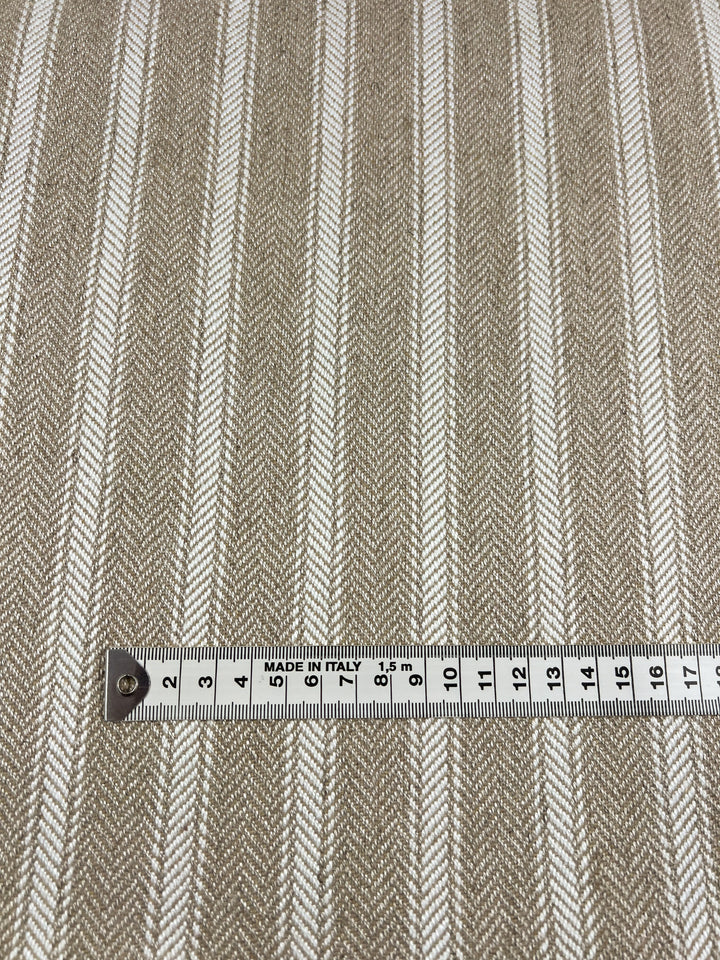 A Super Cheap Fabrics product named Upholstery Herringbone - White & Cream - 145cm, perfect as an upholstery fabric. A measuring tape is laid horizontally across the durable fabric, showing measurements up to 12 centimeters. The measuring tape has a label indicating it was made in Italy.