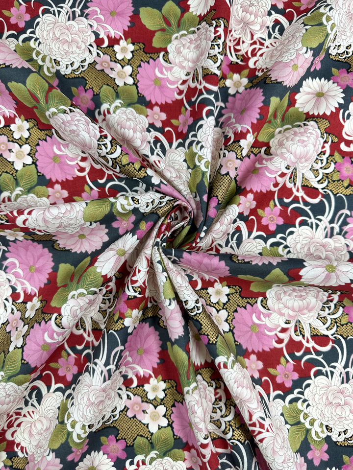 A close-up of Super Cheap Fabrics’ Japanese Printed Cotton - Chrysanthemum (112cm) featuring colorful chrysanthemum floral patterns in pink, white, and red with green leaves, inspired by traditional Japanese motifs and gathered in a spiral.