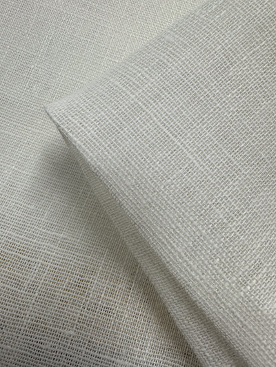 Close-up of Super Cheap Fabrics’ Loose Weave Pure Linen - Off White - 150cm, showing two angled layers with a breathable texture and visible grid pattern.