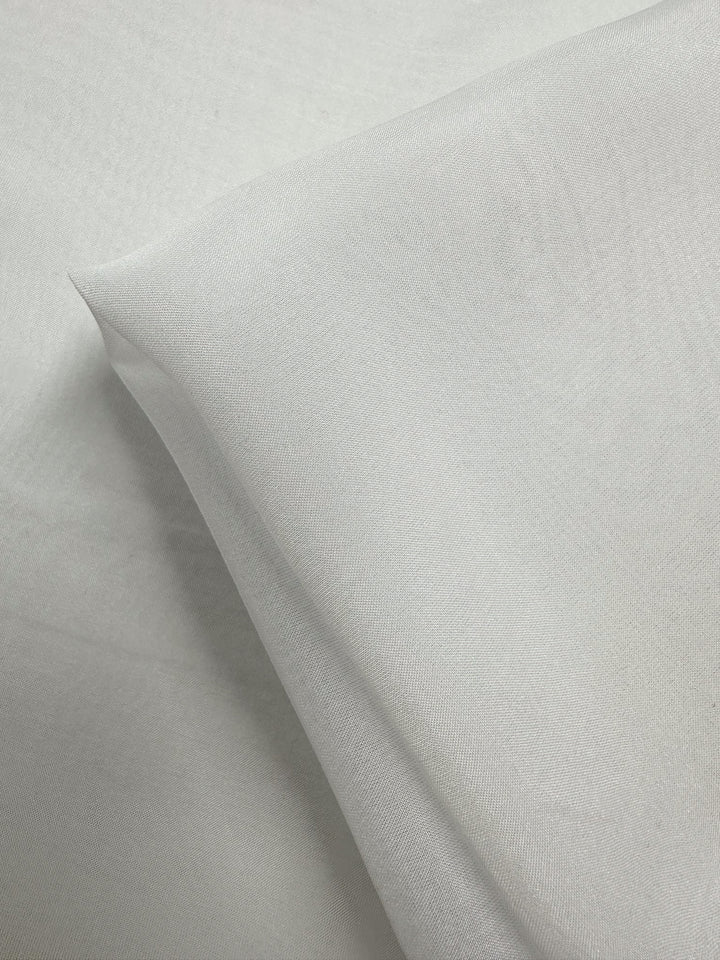 A close-up of Super Cheap Fabrics’ Pure Silk Chiffon in Ivory (140cm), folded to highlight its soft texture and lightweight, semi-sheer quality—ideal for spring and summer garments.
