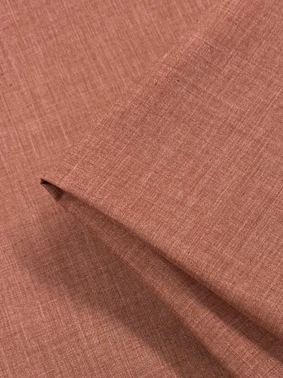 A close-up view of a light brown, textured fabric. The Poplin - Terracotta - 112cm from Super Cheap Fabrics is shown with some slight folds, highlighting its soft, woven appearance. The material appears to be smooth and finely woven, suitable for clothing or upholstery.