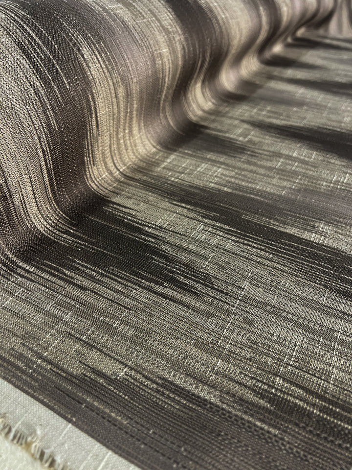 Close-up of a textured, durable fabric with a striped pattern in shades of brown and beige. The Upholstery Jacquard - Walnut - 145cm by Super Cheap Fabrics appears to be draped, showing folds and a woven texture with a mix of dark and light threads, offering an affordable range for stylish interiors.